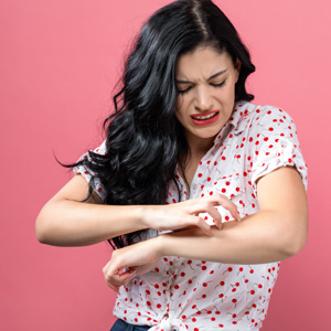 Young woman scratching her itchy arm